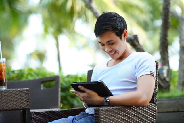 A Student Looking In A Tablet Smiling After Getting Computer Science Homework Help Tutoring Online