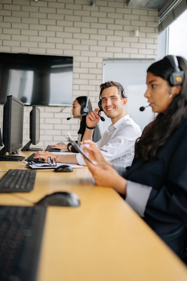3 Persons Sitting In Front Of Computer Screens With Their Headsets On, Representing The Customer Support Tram Of Geeksprogramming.